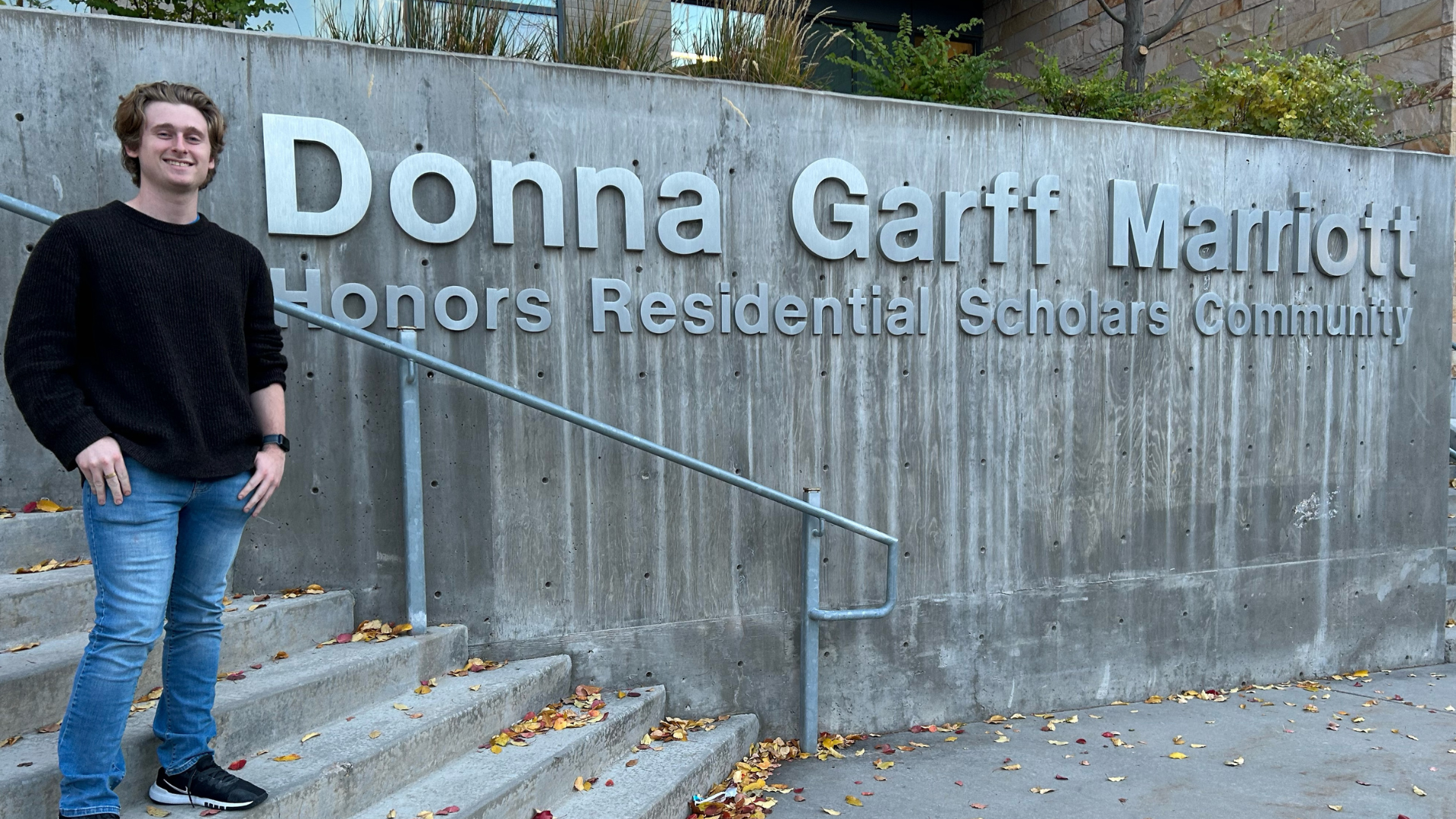 Image of a student next to the Donna Garff Marriott Honors Community sign.